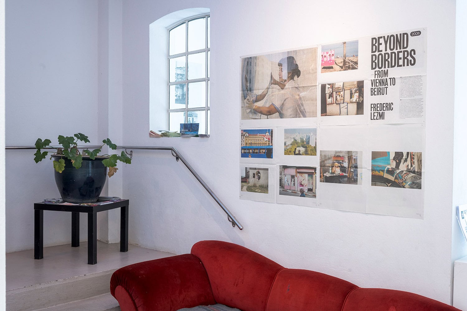 Rotes Sofa und Zeitungsbilder an der Wand