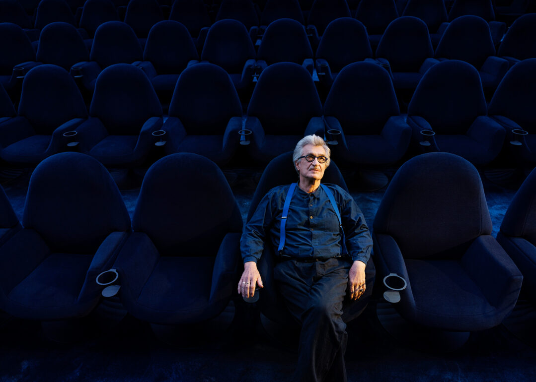 Wim Wenders sitzt in einem blauen Kinosaal