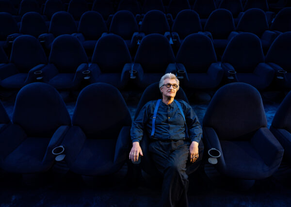 Wim Wenders sitzt in einem blauen Kinosaal