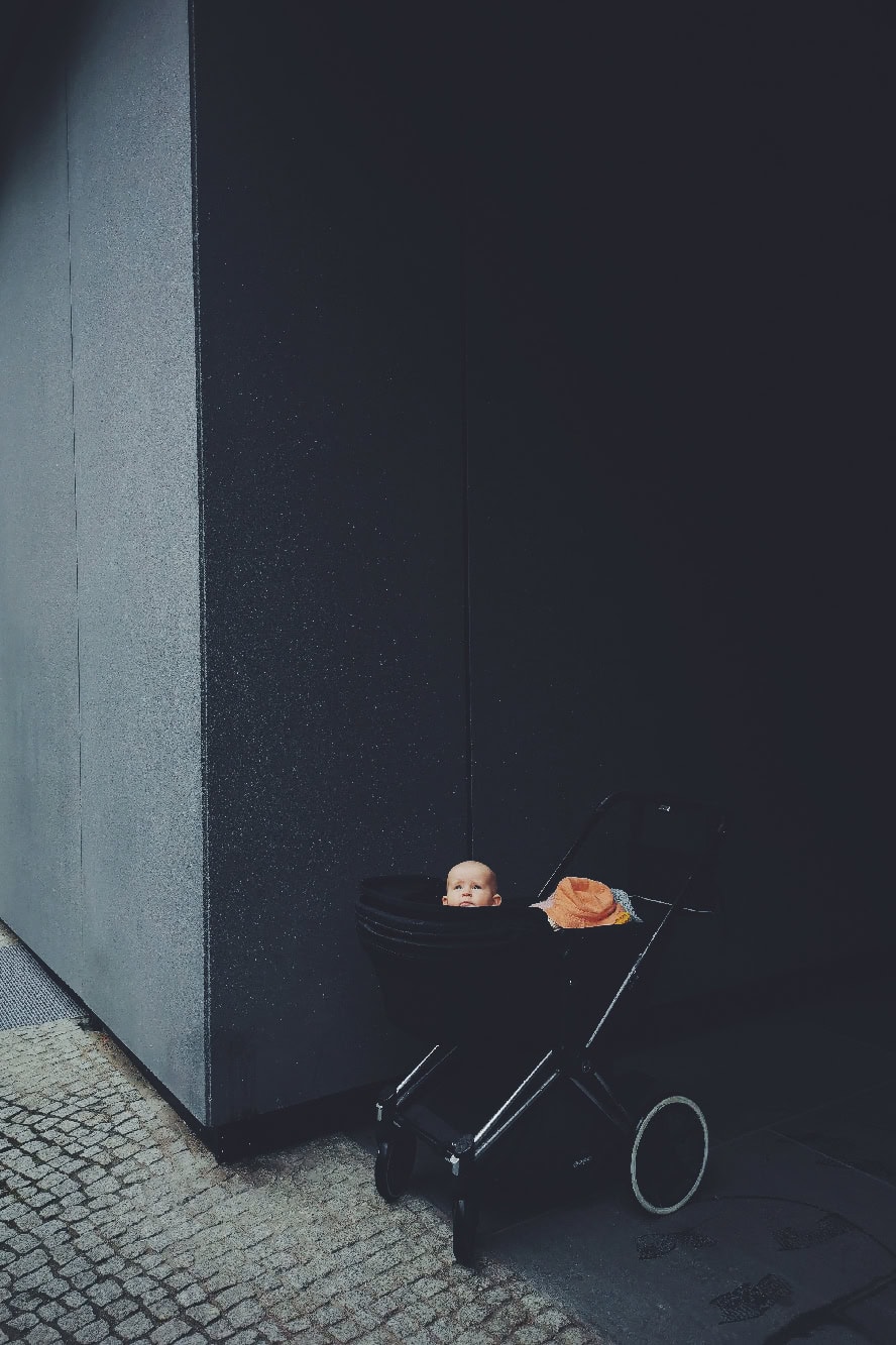 Kinderwagen mit Baby vor moderner dunkler Wand, urbanes Kindertransport-Design, stilvolle Baby-Buggy, modernes Kinderautostyling.