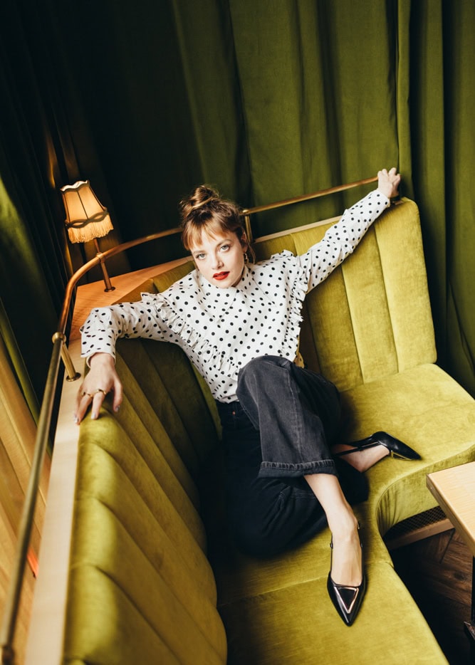 Fotografien im Retro-Stil mit Frau in Polka-Dot-Bluse auf grüner Couch, stilvolle Inneneinrichtung, Fashion, Mode, angesagte Wohnzimmerdekoration, Laif, stilvolles Wohnzimmer.