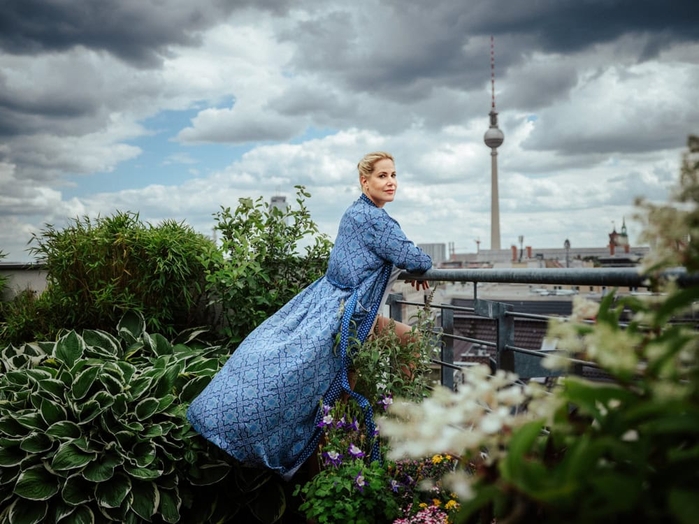 Hochwertige Frau auf Dachgarten mit Blick auf Berlin, TV-Turm und Stadtidylle.