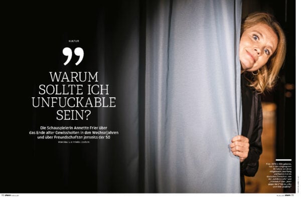 Unsicher und neugierig Annette Frier schaut durch Vorhang, symbolisiert Lebensfreude und Persönlichkeitsentwicklung.