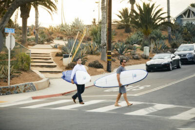 Surfer mit Surfbrett in Santa Monica, Kalifornien gehen über die Straße.