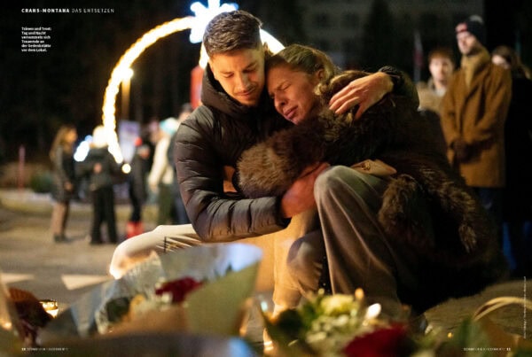 Trauernder Mensch bei Gedenkveranstaltung in Montana, umgeben von Kerzen und Blumen.