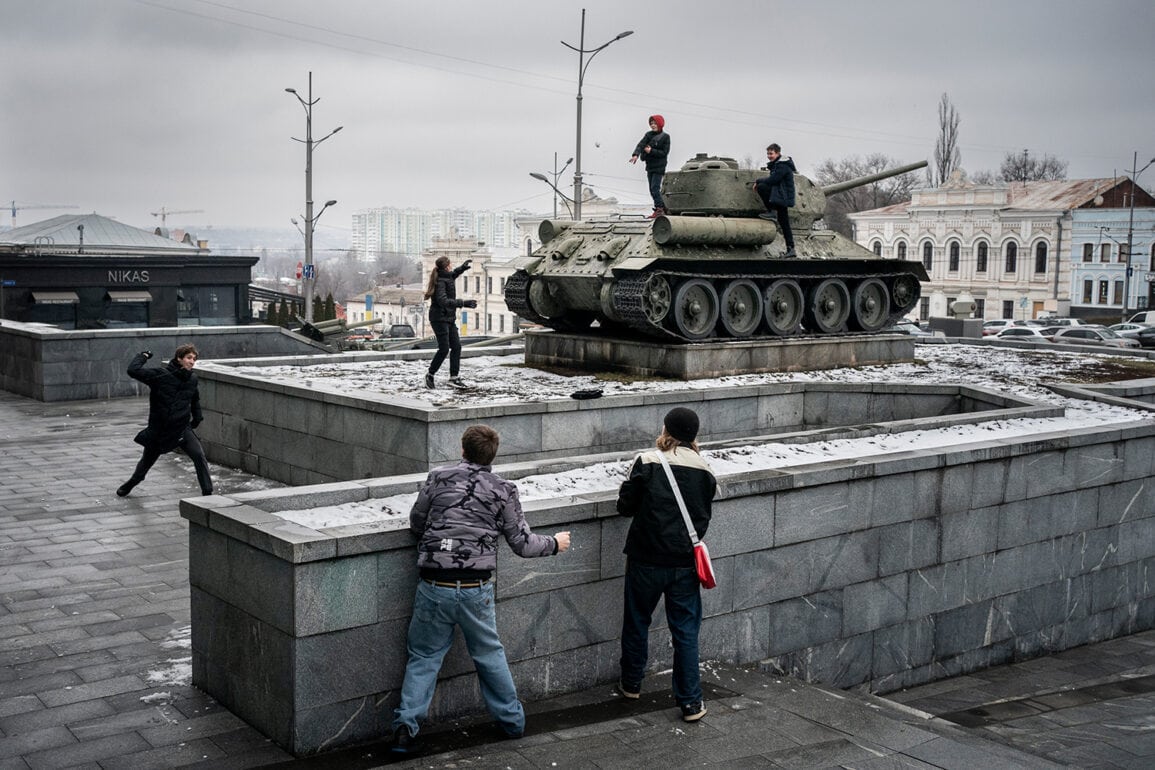 Jugendliche spielen auf einem Denkmal mit einem Panzer in der Stadt.